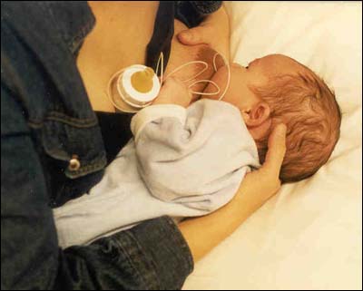 Photo of a woman breastfeeding using a lactation aid